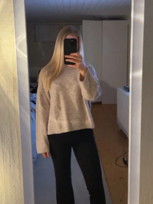 Beige stickad tröja från Gina Tricot - Mysig beige stickad tröja från Gina Tricot med avslappnad passform och rund halsringning. Tröjan har långa ärmar och ribbade muddar vid ärmslut och nederkant. Perfekt för lager på lager och enkel att matcha till olika outfits.