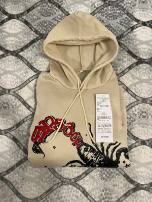 Äkta sp5der hoodie  - Säljer en beige hoodie från sp5der som inte passade mig. Både tjejer och killar kan ha på sig den
