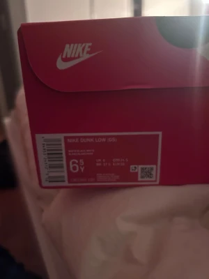 Nike Dunk Low svart/vit sneakers - Nike Dunk Low sneakers i svart och vitt läder med klassisk Swoosh-logga på sidan. Lågt skaft och svart sula. Perfekta för dig som gillar stilrena och tidlösa sneakers med streetwear-vibe.