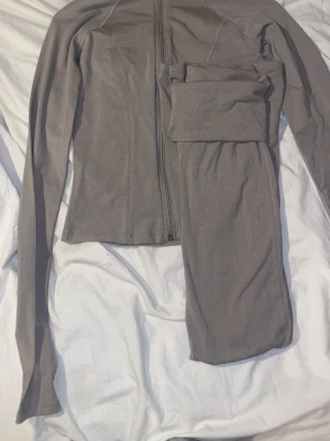 Grått loungewear-set med dragkedja - Mysigt loungewear-set. Setet  av en långärmad tröja med dragkedja framtill och matchande byxor med resår i midjan