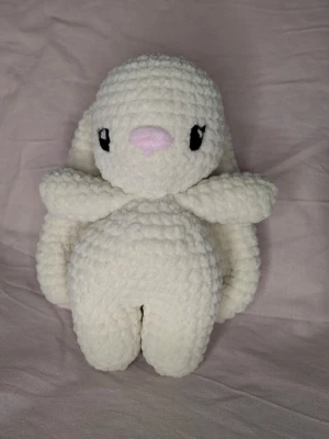 Virkad vit kanin med långa öron - Supergullig handvirkad kanin i mjuk, fluffig vit garn med långa öron och broderad nos i ljusrosa. Svarta broderade ögon ger ett sött uttryck. Kaninen är 19 lång och 15 cm breded armarna. Perfekt som present eller dekoration.