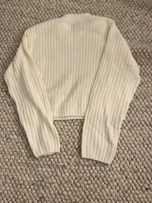 Vit ribbstickad tröja från H&M Divided - Säljer en vit ribbstickad tröja från H&M Divided. Tröjan har lång ärm, rak passform. Perfekt för lager-på-lager och enkel att matcha med olika outfits. Mjuk och skön stickning som håller dig varm.