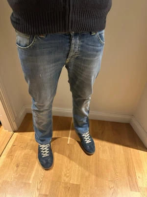 Blå raka jeans med slitningar från dondup - Säljer ett par blå jeans från dondup med raka ben och snygga slitningar framtill. Jeansen har klassiska fem fickor och kontrastsömmar. 
