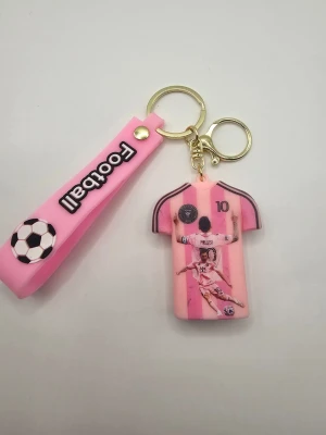 Nyckelring Messi rosa fotbollströja - Cool nyckelring med rosa fotbollströja, inspirerad av Messi och nummer 10. Tröjan har tryck både fram och bak samt en matchande rosa rem med texten 'Football' och en fotboll. Tillverkad i mjukt silikon och metall.