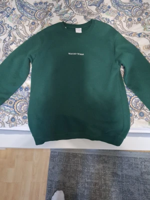 Grön sweatshirt från Selected Homme - Mörkgrön sweatshirt från Selected Homme med enkel design och diskret logga på bröstet. Tröjan har rund halsringning och långa ärmar. Perfekt för en avslappnad och stilren look.