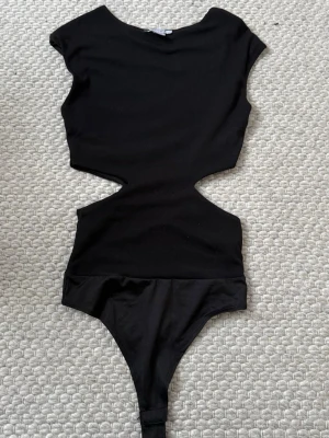 Svart cut out body - Jättefin och populär body från Amisu i strl XS, i perfekt skick. Finns inte att köpa i butik längre🩷
