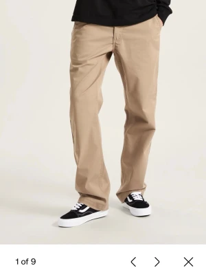 Beiga chinos från Vans  - Klassiska beiga chinos från Dickies med rak passform och normal midja. Byxorna har sidfickor och är tillverkade i ett slitstarkt bomullsmaterial. Perfekta för en avslappnad och stilren look.
