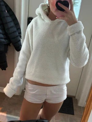 Vit teddy hoodie med huva - Mysig vit hoodie i teddy-material med huva och långa ärmar. Perfekt för dig som gillar en avslappnad och trendig look. Sååå mysig och unik! 