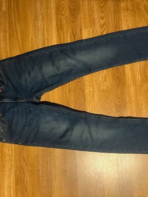 Mörkblå (slim) jeans från Tommy Hilfiger - VET INTE VARFÖR BILDERNA ÄR INZOOMADE SKRIV OM NI VILLL SE NORMALT! Snygga mörkblå skinny jeans från Tommy Hilfiger med klassisk femficksmodell och diskret logga på bakfickan. Jeansen har slim passform och är tillverkade i stretchigt denimtyg för extra komfort. Perfekt för den som vill klä sig med stil och comfort 
