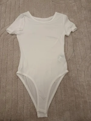 3 basic bodys i vit, beige och svart - Säljer 3  bodys med korta ärmar, en i vit, en i beige och en i svart. Alla har rund halsringning och är tillverkade i ett mjukt och stretchigt material som känns skönt mot huden. Perfekt att matcha med jeans eller kjol för en enkel och clean look.