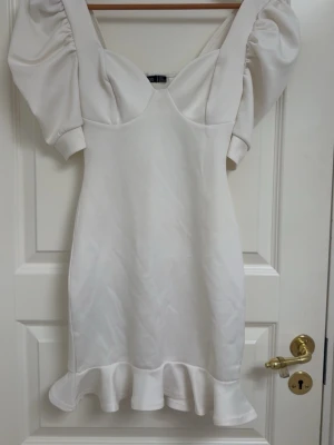 Vit kort klänning med puffärm och volanger - Använt endast en gång! En vit kort klänning med puffärmar och volangkant nertill. 