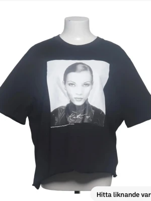 Svart t-shirt med fototryck - Cool svart t-shirt med stort fototryck framtill och textdetalj under bilden. T-shirten har en avslappnad passform och klassisk rund hals. Perfekt för dig som gillar streetwear och grafiska prints.