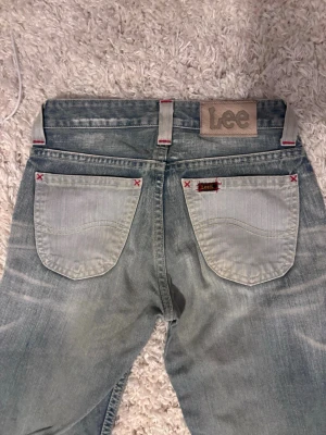 Vintage lee bootcut jeans - Säljer ett par vintage jeans från Lee som är från början av 200s,  med kontrastfärgade bakfickor och röda detaljer vid fickhörnen. Jeansen är lågmidjade med bootcut och Lee-lap✨ midjemått: 32 cm innerbenslängd: 80 cm