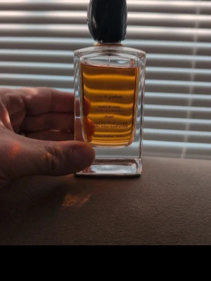 Si Giorgio Armani  - Snygg parfym i en rektangulär glasflaska med svart kork och bärnstensfärgad vätska. Flaskan har stilrena linjer och text i guld på framsidan. Perfekt för dig som gillar lyxiga dofter och elegant design.