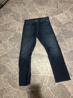 Mörkblå jeans från replay - Snygga mörkblå jeans från replay med klassisk femficksdesign och raka ben. Perfekta för dig som gillar en tidlös och stilren look. Passformen är regular fit och passar allt från 170-180. Använda max 5 gånger
