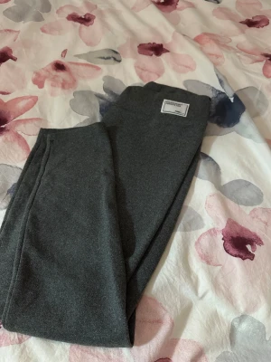 Mörkgrå fleecefodrade leggings - Mysiga mörkgrå leggings från Urban Classics med mjukt fleecefoder på insidan. Perfekta för kalla dagar när du vill ha både stil och komfort. Stretchigt material som sitter skönt och följsamt på kroppen.