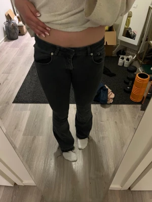 Gråa bootcut jeans - Säljer ett par svarta bootcut jeans med klassisk femficksdesign. Jeansen har en snygg tvätt och raka ben som går ut lite nedtill. Perfekta till en avslappnad stil och passar till det mesta. Materialet är mjukt denim för skön känsla. Perfekt nu till sommaren