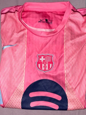 Rosa FC Barcelona matchtröja  - Säljer en rosa FC Barcelona matchtröja med klubbmärke och Spotify-logga på framsidan. Tröjan har trycket 'LAMINE YAMAL' och nummer 10 på ryggen. Tillverkad i lätt, ventilerande material. Passar mig som har S/XS