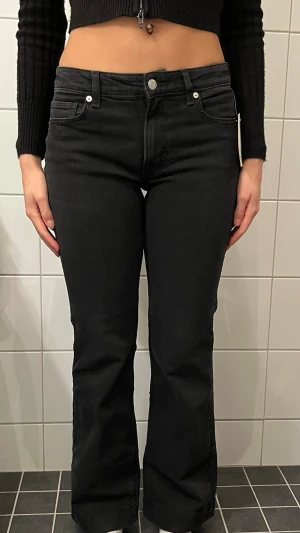 Svarta bootcut jeans med hög midja - Snygga svarta bootcut jeans med hög midja och klassiska fem fickor. Jeansen har en figurnära passform upptill och utsvängda ben. Perfekta för dig som vill ha en trendig siluett och matcha med allt från sneakers till boots.