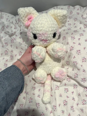 Virkad vit katt🤍 - Virkad vit fluffig katt i ”coquette” stil med rosa fläckar och en söt rosa rosett vid örat.🩷🎀