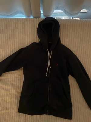 Ralph Lauren Sip up - Mörkblå sip up från Ralph Lauren, från början köpt på NK. I väldigt bra skick förutom ett av snörena är lite skadat (se sista bilden) men det är inget man tänker på.