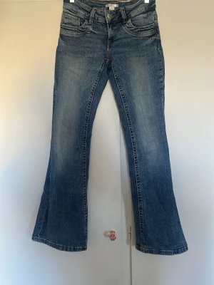 Blå bootcut jeans - Ett par klassiska blå bootcut jeans med fem fickor. Jeansen har en något utsvängd passform nedtill och är tillverkade i denim. Perfekta för en avslappnad och trendig look. De är ifrån Gina Tricot och är i storleken 158. 
