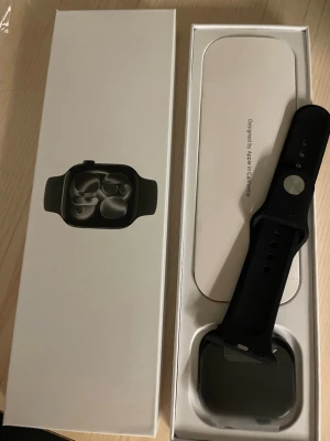 Apple Watch svart aluminium - Snygg Apple Watch med svart aluminiumboett och svart silikonarmband. Klockan har en fyrkantig form med rundade hörn och en stor, tydlig pekskärm. Kommer i originalförpackning med instruktioner. Perfekt för dig som vill ha koll på notiser och hälsa direkt på handleden.