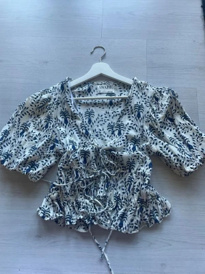 Blommig topp med puffärm från Aware - Söt topp från Aware! Nytt skick då jag tänkte ge bort den i present men blev aldrig av!          Storlek S/M då den är stretchig vid midjan