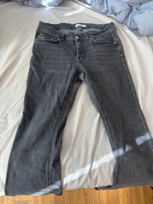 Svarta raka jeans - Säljer ett par svart jeans med rak passform och klassisk femficksdesign. Jeansen har knappgylf. Materialet är denim med en mjuk känsla. Perfekta för en avslappnad och stilren look.