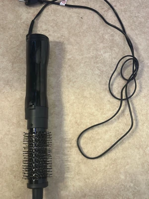 Svart varmluftsborste med sladd - Elektrisk varmluftsborste i svart plast med rund borste och täta borststrån. Perfekt för att styla och forma håret med volym. Utrustad med lång sladd för enkel användning. Passar dig som vill fixa frisyren snabbt och smidigt.