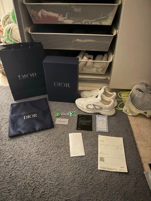 Vita Dior B30 sneakers - Säljer ett par vita Dior B30 sneakers med chunky sula och futuristisk design. Skorna har mesh och läderdetaljer, samt tydliga Dior-loggor på sulan. Kommer med originalkartong, dustbag och tillbehör. Perfekta för dig som vill sticka ut med exklusiva sneakers.