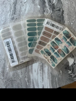Mixade nagelstickers i olika färger - Säljer ett set med nagelstickers i flera olika designer och färger. Innehåller glitter-silver, teal, beige med svart mönster samt marmorerade blå/rosa motiv. Perfekt för dig som vill fixa snygga naglar snabbt och enkelt hemma.