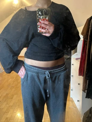 Svart croppad långärmad topp - Svart croppad topp med lång ärm och bred halsringning. Toppen har en loose passform och är gjord i mjukt bomullsmaterial. Köpt från lager 157 men min moster som är syslöjds lärare har sytt om hela tröjan men det syns inte