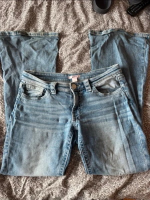 lågmidjade Ljusblå bootcut jeans med slitningar - från gina tricot young 14+ i storlek m. Säljer ett par ljusblå bootcut jeans med snygga slitningar och tvättade detaljer. Klassisk femficksmodell med bälteshällor och dragkedja. Bakfickorna har dekorativa sömmar. Perfekta för en avslappnad och trendig look.