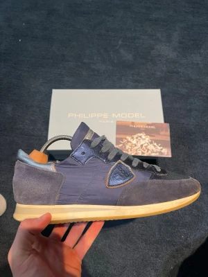 Philippe Model skor - Snygga sneakers från Philippe Model i marinblått tyg och mocka med. Skorna är använda fåtal gånger och i väldigt fint skick. Perfekta för dig som gillar stilrena och exklusiva sneakers. Bara att höra av dig vid frågor😃