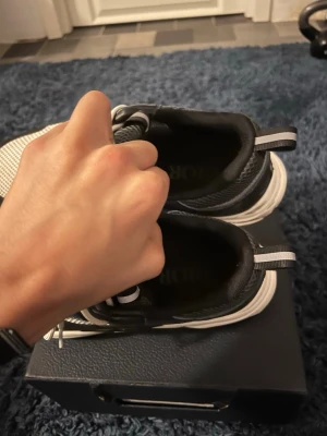 Svarta och vita b22 sneakers - Säljer ett par snygga b22 sneakers i svart och vitt med meshdetaljer och robust sula. Skorna har låga skaft och reflekterande detaljer på hälen. Perfekta för dig som vill ha en exklusiv och trendig look. Är du intresserad eller har frågor är det bara att skriva. Pris går att diskutera.