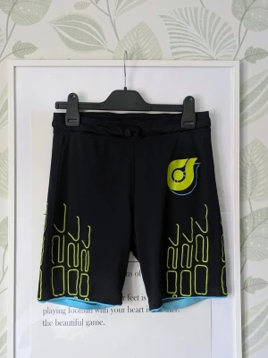 Woxo KappAhl Träningsshorts Storlek 152 -  I fint skick .  Småsprickor förekommer i trycken .  Lite nopper kan synas inne i sömkanter/resår och det här gått upp i sömmen framtill i midjeresårens söm kanske ca 6 cm..  - Jag kan ha missat någon miniskavank men jag har försökt att granska plagget så gott det går