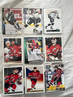 Samling hockeykort NHL 90-tal - Säljer en samling med nio hockeykort från NHL, mestadels med spelare från New Jersey Devils och några från andra lag. Korten har färgstarka bilder, statistik och spelarinfo på baksidan. Perfekt för dig som gillar hockey och vill utöka din kortsamling.