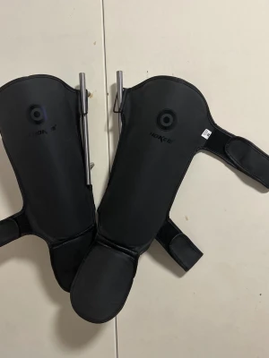 Benskydd till kampsport - Benskydd i nyskick, används vid kampsport Storlek M, (finns spännen där man kan reglera hur hårt eller löst den ska sitta) Pris kan diskuteras vid snabb affär!