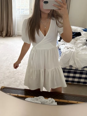 Söt sommar klänning - Supersöt vit sommar klänning med en liten rosett från GinaTricot, används 1 gång och är i helt nytt skick. Jätte fin till sommaren och skolavslutning!!