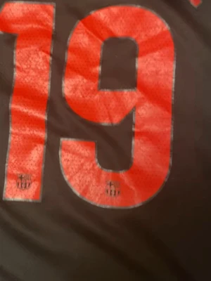 FC Barcelona matchtröja svart/röd - Säljer en svart FC Barcelona matchtröja från Nike med stora röda siffror och texten 'YAMINE' på ryggen. Tröjan har ventilerande meshmaterial och klubbens emblem tryckt på siffrorna. Perfekt för dig som älskar fotboll och vill sticka ut på planen.