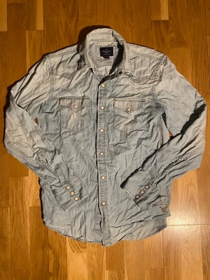 American Eagle jeansskjorta - En snygg ljusblå jeansskjorta från American Eagle i storlek XS. Inga deefekter förutom att den sista knappen inte fungerar. Ifall fler frågor eller bilder skriv!🤗