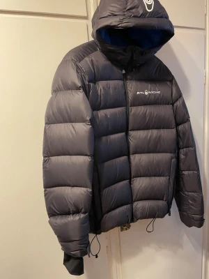 Svart dunjacka från Sail Racing  - Säljer en svart dunjacka från  Sail Racing! Jackan är svart men går mer åt grå hållet med blå innersida. Inga defekter och super bra skick! Skriv gärna ifall du har några funderingar eller vill ha fler bilder! Kan gå ner i pris vid snabb affär!