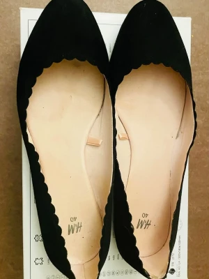 Svarta ballerinaskor från H&M - Stilrena svarta ballerinaskor från H&M med vågig kant runt öppningen. 
