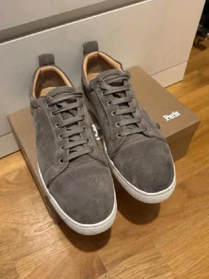 Grå mockasneakers från Christian Louboutin - Snygga grå sneakers i mocka från Louboutin. Skorna har vita sulor, grå skosnören och diskreta detaljer. Insidan är fodrad i beige läder för extra komfort. Perfekta för dig som gillar stilrena och klassiska sneakers med en modern touch. No Box. Pris kan diskuteras.