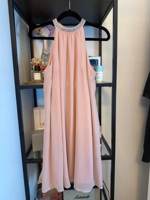 Ljusrosa klänning med strassdetalj - Jätte söt CelebrationbyMohito klänning! ljus rosa som skimrar vid ljus. och fin sten detalj längst haldsen. Tyvärr har den fått en defekt längst bak men syns inte riktigt.se bild 4,5!