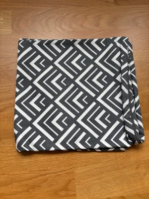 Svartvitt kuddfodral med grafiskt mönster 50x50 - Säljer ett kuddfodral i svart och vitt med ett snyggt grafiskt mönster av pilar och linjer. Fodralet är fyrkantigt och har dragkedja på ena sidan. Perfekt för att ge soffan eller sängen en modern touch.