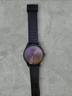 Snygg klocka - Stilren svart klocka  med rund urtavla och svart silikonarmband. Urtavlan har minimalistisk design med diskreta visare och märkets logga perfekt för alla outfits 