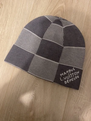 Mössa från Vuitton - Säljer en grå mössa från Vuitton med rutmönster i olika nyanser av grått. Mössan har broderad text 'Marque L. Vuitton Deposee' och en vävd etikett på insidan. Klassisk och stilren design som sticker ut.endast testad en gång🤩