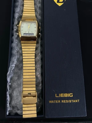 Herr klocka  - Snygg guldig klocka från Liebig med både analog och digital display. Klockan har en rektangulär urtavla med guldfärgade detaljer och länkarmband i metall. Enkel och stilren design som sticker ut.